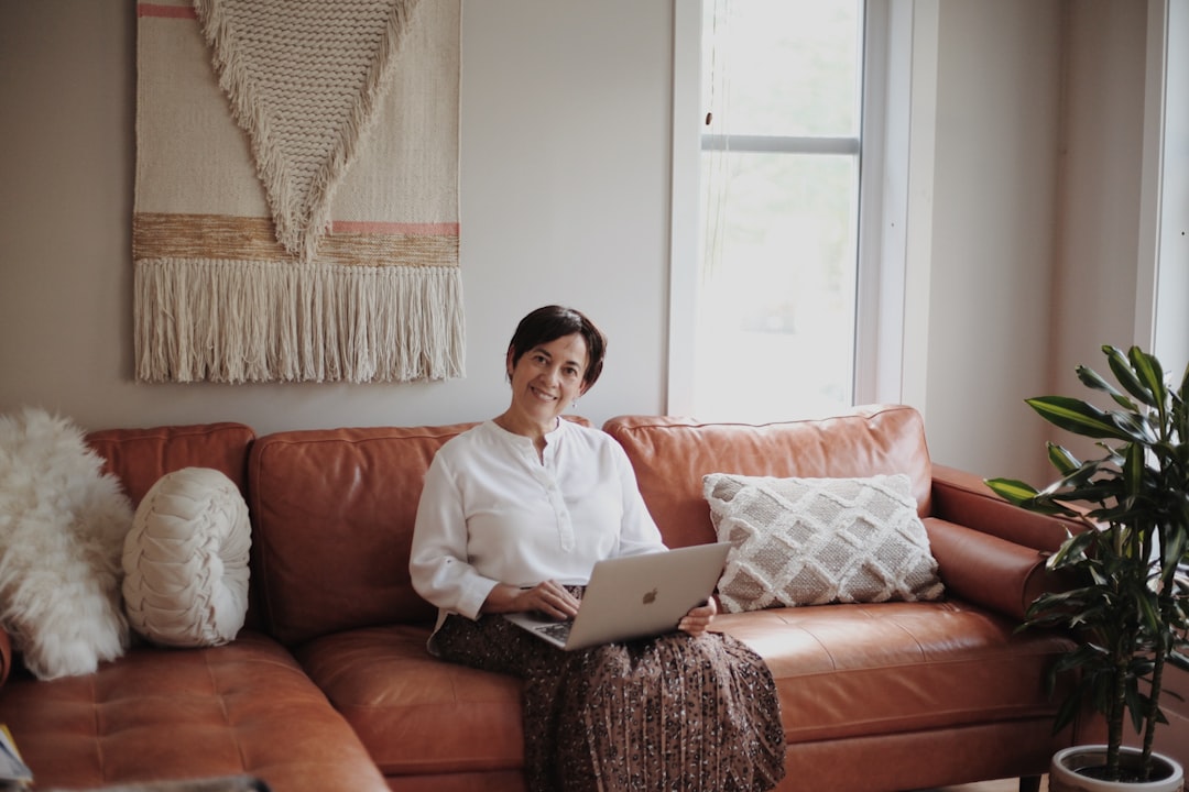 Photo by Samia Liamani man in white dress shirt sitting on red couch using macbook